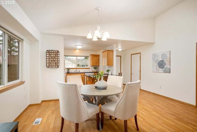 dining area with visible vents, baseboards, a chandelier, light wood-type flooring, and lofted ceiling