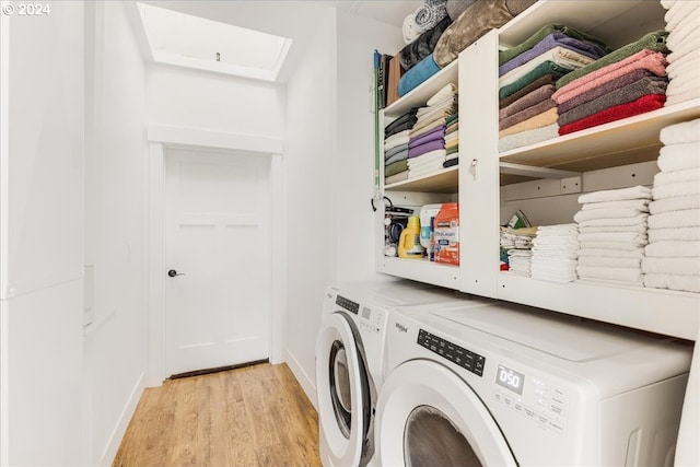washroom with washing machine and clothes dryer and light hardwood / wood-style flooring