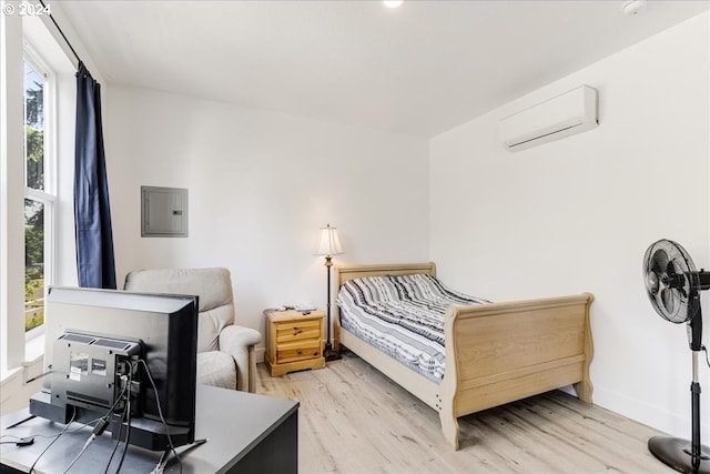 bedroom featuring electric panel, light hardwood / wood-style flooring, and a wall unit AC