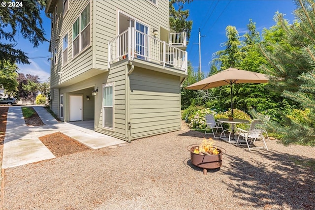 view of side of home with a balcony, a patio area, and a fire pit