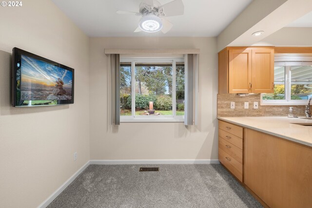 kitchen featuring ceiling fan, a healthy amount of sunlight, light carpet, and tasteful backsplash