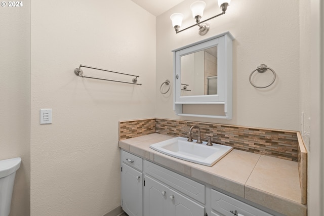 bathroom with vanity, backsplash, and toilet