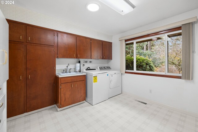 laundry room featuring cabinets, sink, and washing machine and clothes dryer