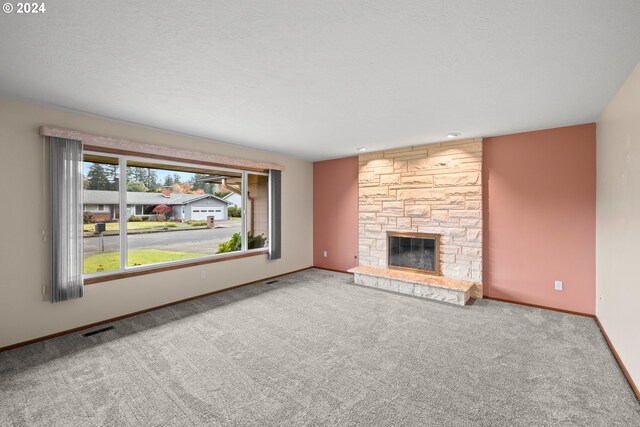 unfurnished living room with carpet flooring and a stone fireplace