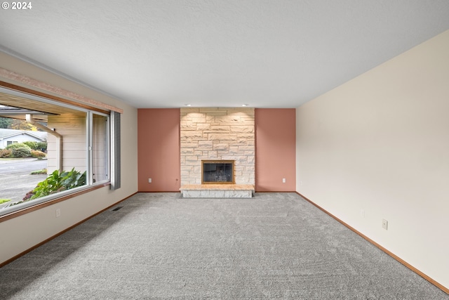 unfurnished living room with carpet flooring, a fireplace, and a textured ceiling