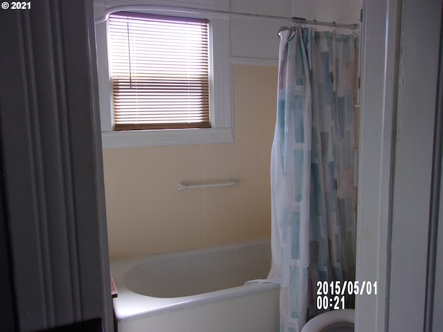 bathroom featuring shower / bath combination with curtain and toilet