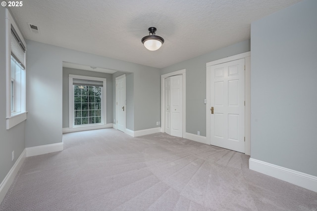 unfurnished bedroom with carpet flooring, visible vents, a textured ceiling, and baseboards