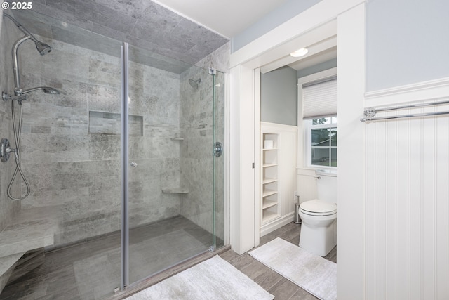 bathroom featuring a stall shower, toilet, and wood finished floors