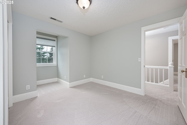 unfurnished room featuring visible vents, carpet floors, a textured ceiling, and baseboards