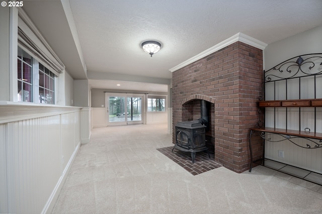 unfurnished living room featuring carpet flooring, a textured ceiling, and a wood stove