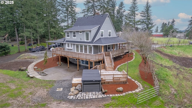 rear view of property with a patio, stairway, fence, driveway, and roof with shingles