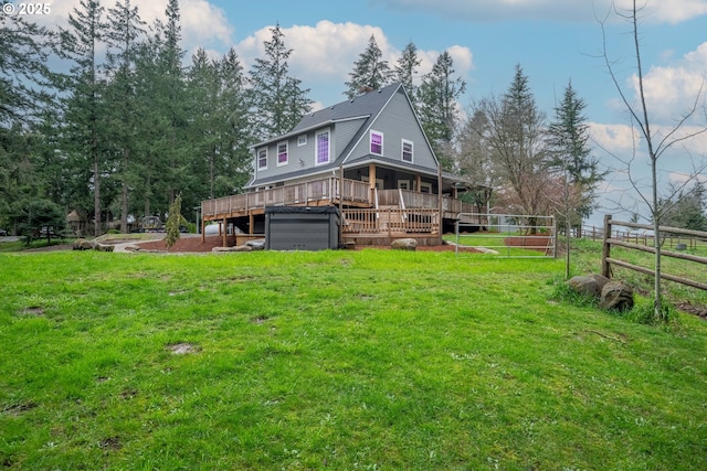 rear view of property featuring a wooden deck, a lawn, and fence