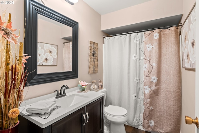 bathroom with a shower with shower curtain, hardwood / wood-style floors, vanity, and toilet