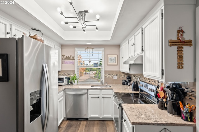 kitchen featuring light stone counters, sink, white cabinetry, stainless steel appliances, and an inviting chandelier