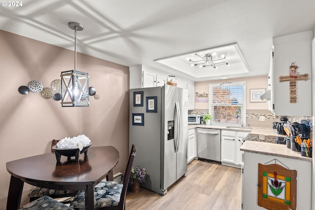 kitchen featuring sink, white cabinets, hanging light fixtures, decorative backsplash, and appliances with stainless steel finishes