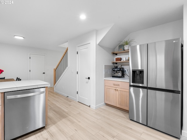 kitchen featuring light brown cabinetry, tile counters, stainless steel appliances, and light hardwood / wood-style floors