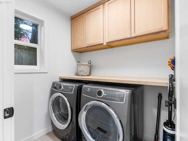 laundry room with washer and clothes dryer, light hardwood / wood-style flooring, and cabinets