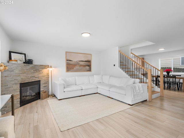 living room with a stone fireplace and light wood-type flooring