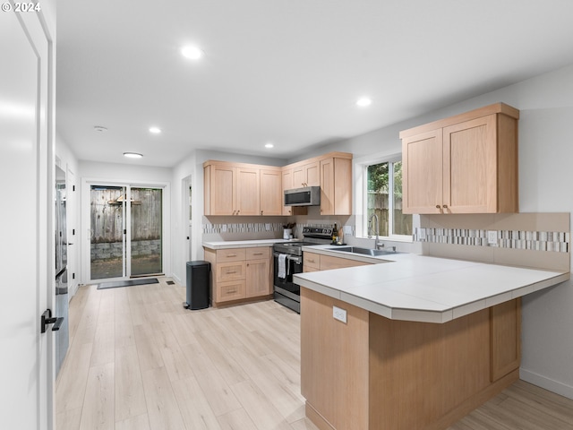 kitchen featuring kitchen peninsula, light brown cabinets, sink, light hardwood / wood-style floors, and stainless steel appliances