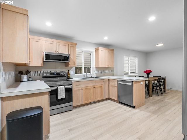 kitchen with light hardwood / wood-style floors, stainless steel appliances, sink, and light brown cabinetry