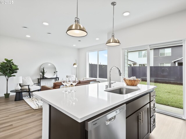 kitchen with a sink, open floor plan, light countertops, stainless steel dishwasher, and an island with sink