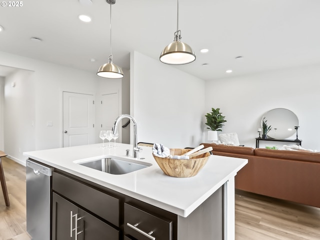 kitchen with a sink, open floor plan, light countertops, dishwasher, and a center island with sink