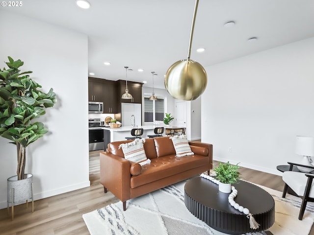 living area with baseboards, light wood-type flooring, and recessed lighting