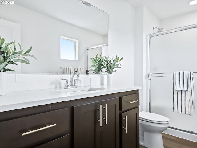 bathroom with a stall shower, visible vents, toilet, wood finished floors, and vanity