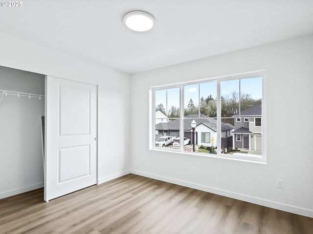 unfurnished bedroom featuring a closet, light wood-type flooring, and baseboards