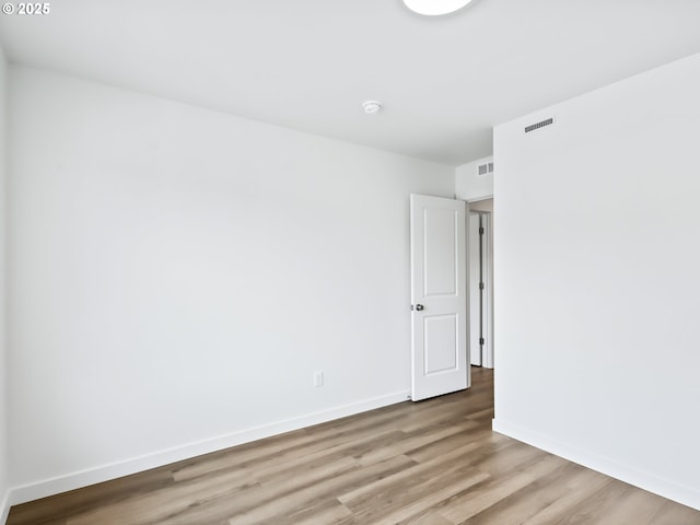 unfurnished room with light wood finished floors, visible vents, and baseboards