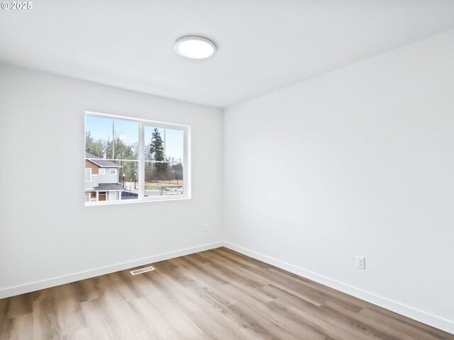 unfurnished room featuring visible vents, light wood-style flooring, and baseboards