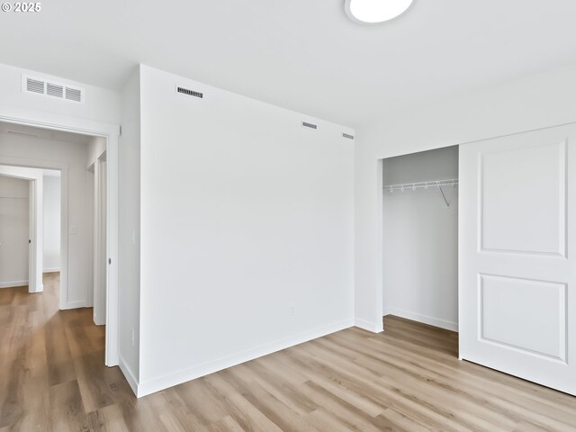 unfurnished bedroom with visible vents, light wood-style flooring, and baseboards