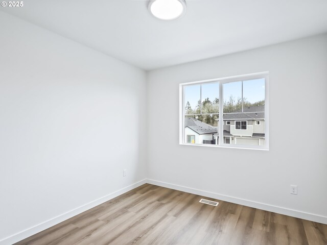 unfurnished room with light wood-style floors, baseboards, and visible vents