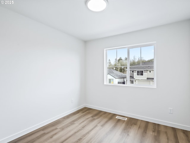 spare room with visible vents, light wood-style flooring, and baseboards