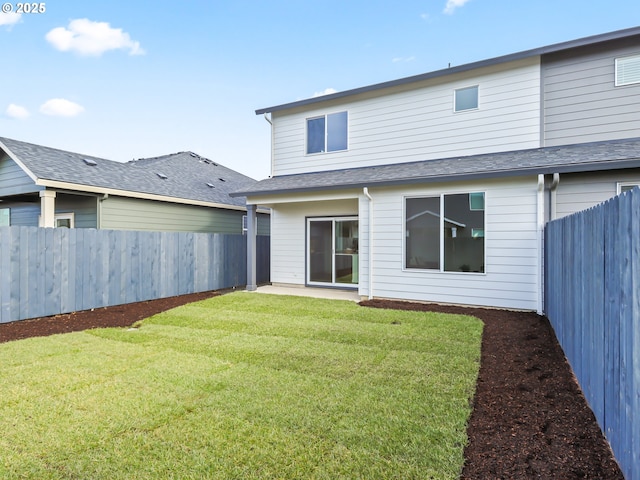 back of property with a fenced backyard, a yard, and roof with shingles