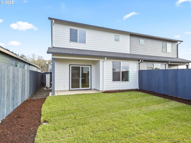 back of house featuring roof with shingles, a lawn, a patio area, and a fenced backyard