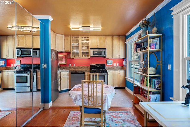 kitchen with stainless steel appliances, light brown cabinets, hardwood / wood-style flooring, and crown molding