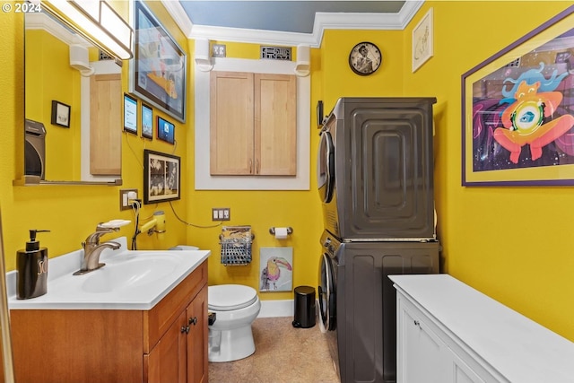 bathroom featuring toilet, crown molding, vanity, and stacked washer and dryer