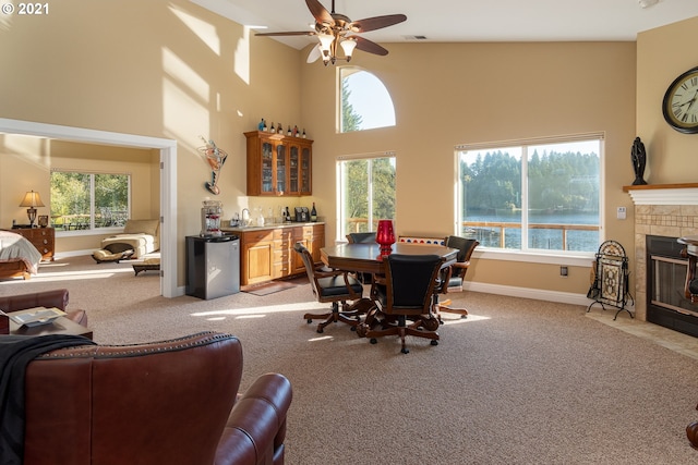 carpeted dining area featuring high vaulted ceiling, plenty of natural light, ceiling fan, and a fireplace