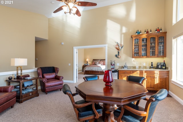 carpeted dining room featuring ceiling fan and a high ceiling