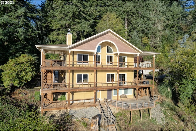 back of house with a wooden deck and a balcony