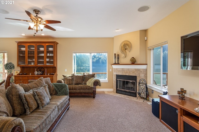 carpeted living room with ceiling fan and a tile fireplace