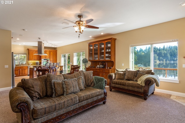 tiled living room with rail lighting, a wealth of natural light, and ceiling fan