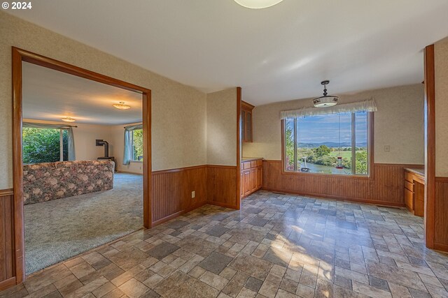 carpeted spare room with wood walls