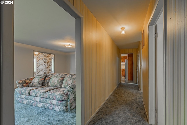 hall with carpet floors and wood walls