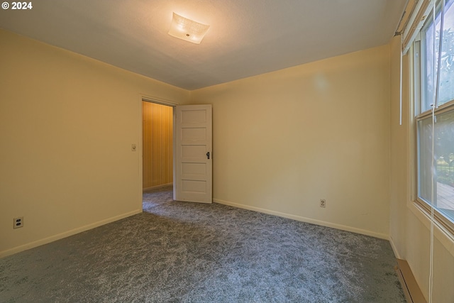 91235 N Bank Ln, Coquille, OR 97423 - empty room featuring baseboards, dark colored carpet, and a wealth of natural light