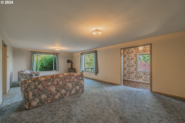 91235 N Bank Ln, Coquille, OR 97423 - living room featuring carpet flooring, a healthy amount of sunlight, a wood stove, and baseboards