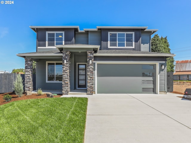 prairie-style house featuring a garage, a front yard, fence, and driveway