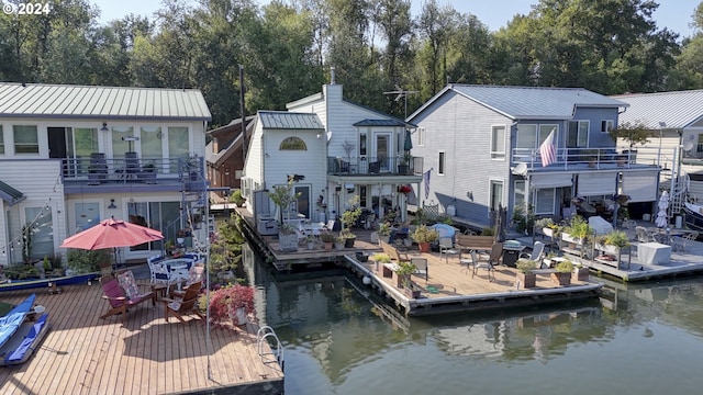 back of property featuring a balcony, a patio area, and a water view