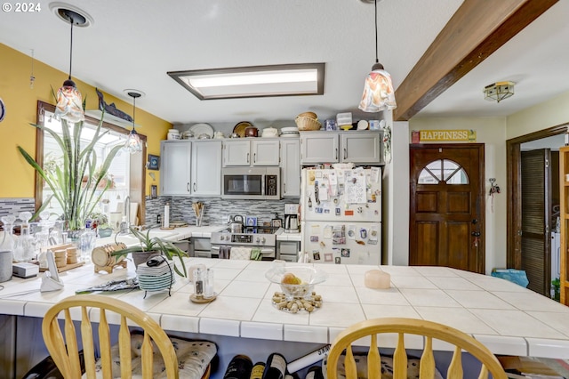 kitchen featuring appliances with stainless steel finishes, a kitchen breakfast bar, tile counters, and hanging light fixtures